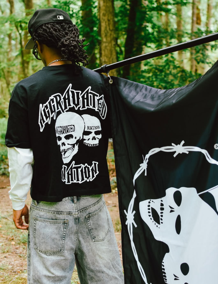 Model holding Aggravated Nation skull flag in the woods